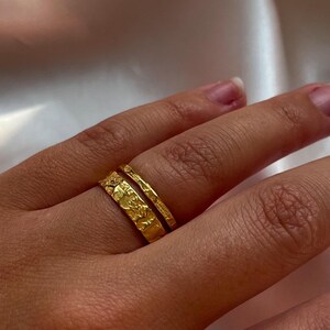 Pu&ograve; includere: Due anelli d'oro impilati su un dito. L'anello superiore &egrave; una fascia sottile con una texture martellata. L'anello inferiore &egrave; pi&ugrave; largo e ha una texture martellata pi&ugrave; intricata.