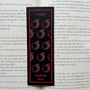 May include: A black bookmark with a red apple pattern and the text "Twilight" and "Stephanie Meyer".