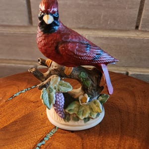 ブドウの木に止まったヴィンテージの赤いカーディナル陶器の鳥