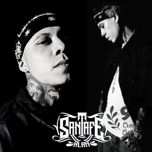 May include: Black and white photo of a man with tattoos wearing a black bandana and a black shirt. The man is looking to the side. The image has the text "SANIAFE KLAN" in white letters with a black and white leaf design.