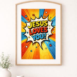 以下が含まれることがあります： 「JESUS LOVES YOU！」のメッセージが吹き出しに入った、額入りのポップアートプリント。黄色、オレンジ、青、赤の鮮やかな配色で、星のアクセントが施されています。プリントは木製のテーブルに飾られています。