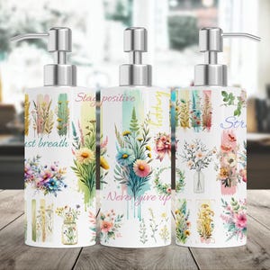 May include: Three white ceramic soap dispensers with silver pumps. Each dispenser features a different floral design and inspirational text. The text on the dispensers reads "Stay positive", "Just breath", and "Never give up".