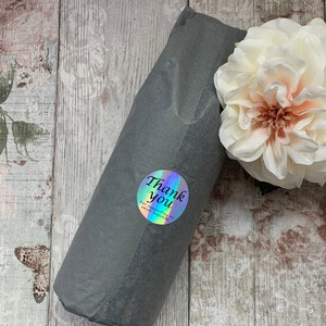 May include: A gray gift bag with a holographic sticker that says "Thank you for supporting my small business". The bag is on a wooden surface with a white flower.