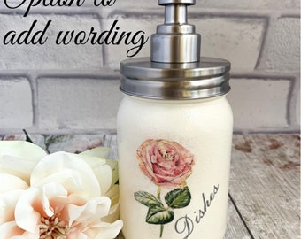 May include: White ceramic soap dispenser with a stainless steel pump and lid. The dispenser features a pink rose and the word "Dishes" printed on it.