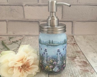 May include: A blue and white ceramic soap dispenser with a stainless steel pump and a floral design. The dispenser is sitting on a wooden surface.