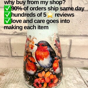 May include: A white ceramic vase with a robin design. The vase has a distressed look and features three robins perched on branches with red flowers. The text "why buy from my shop?" is written above the vase. The text "90% of orders ship same day" is written below the vase. The text "hundreds of 5 star reviews" is written below the vase. The text "love and care goes into making each item" is written below the vase.