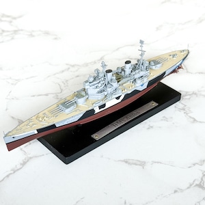 May include: A detailed model of the HMS Anson battleship, featuring a gray and white superstructure, a tan deck, and a black and red hull. The model sits on a black base with a nameplate that reads "HMS Anson".