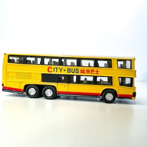 May include: A yellow toy double-decker bus with black accents and the text "CITY 'N BUS 城市巴士" on the side.