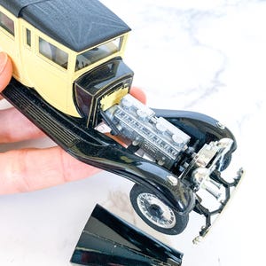 May include: A black and yellow toy car with a detailed engine and a removable hood. The car is missing its front grill.
