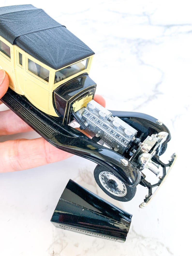 May include: A black and yellow toy car with a detailed engine and a removable hood. The car is missing its front grill.