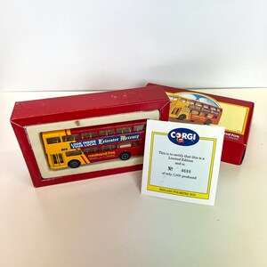 Może przedstawiać: Zabawka w postaci czerwonego i żółtego autobusu piętrowego w czerwonym pudełku z białą etykietą, na której widnieje napis "Look Inside Your Local Leicester Mercury Midland Fox". Pudełko zawiera również białą kartkę z logo Corgi i tekstem "This is to certify that this is a Limited Edition and is: No. 4688 of only 5,000 produced Midland Fox Metro Bus."