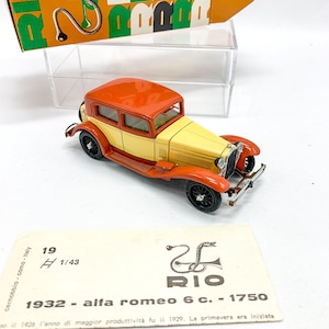 Puede incluir: Un coche modelo Alfa Romeo 6C 1750 de 1932 de color rojo y crema a escala 1/43. El coche se muestra en una tarjeta blanca con el logotipo de RIO y texto en italiano.