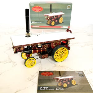 Puede incluir: Un modelo rojo y dorado de una máquina de vapor Burrell Showmans, llamada "Edward Hines' Golden Dragon", con una plataforma blanca y una chimenea negra. El modelo forma parte de la colección Corgi Vintage Glory.