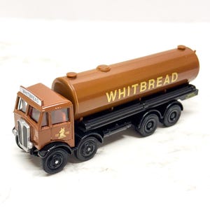 May include: A brown toy tanker truck with the word "WHITBREAD" in gold lettering on the tank. The cab of the truck also has the word "WHITBREAD" and the year "1742" printed on it. The truck has black wheels.