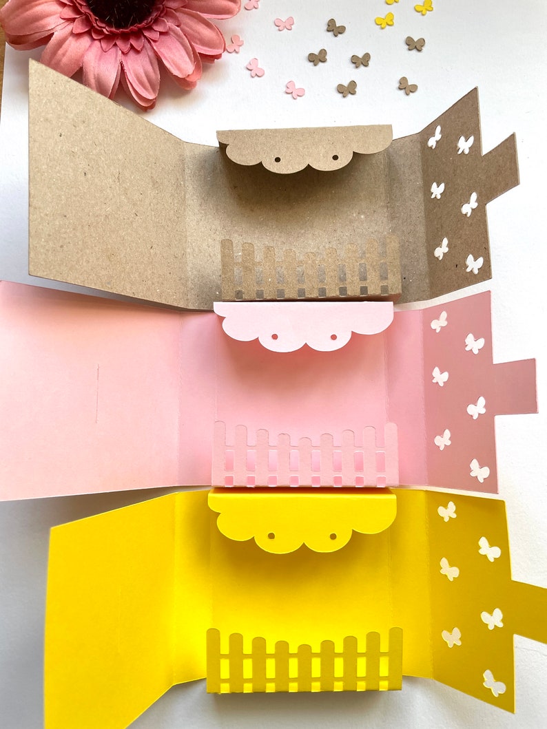 May include: Three open card boxes with different colored paper. The top box is brown with a brown fence and butterflies. The middle box is pink with a pink fence and butterflies. The bottom box is yellow with a yellow fence and butterflies.