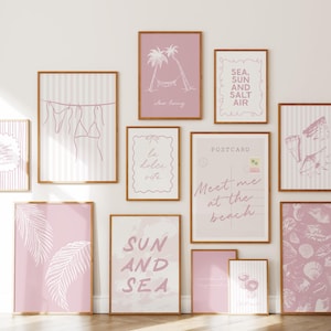 May include: A gallery wall arrangement of twelve framed art prints in shades of dusty pink and white. The prints feature line drawings of palm trees, seashells, bikinis on a clothesline, and text including "Sun and Sea" and "Meet me at the beach."