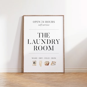 May include: A framed print with the text "THE LAUNDRY ROOM" in a bold font. The top of the print reads "OPEN 24 HOURS self service." Below the text are watercolor illustrations of laundry items, including a washing machine and iron.