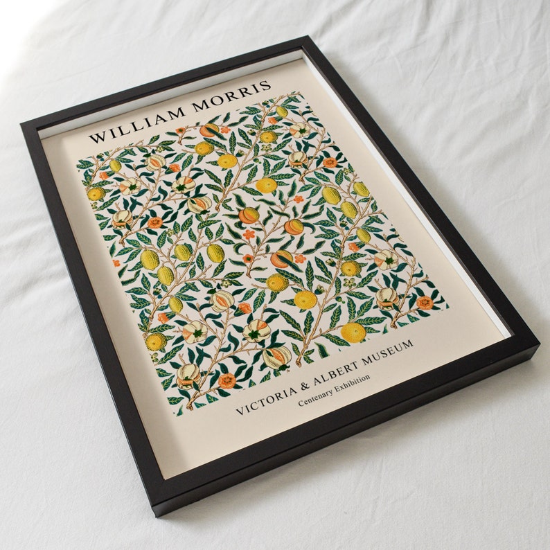 Puede incluir: Un estampado enmarcado con un dise&ntilde;o bot&aacute;nico de frutas amarillas y naranjas, hojas verdes y flores blancas sobre un fondo crema. El estampado est&aacute; en un marco negro. El texto "WILLIAM MORRIS" y "VICTORIA & ALBERT MUSEUM" son visibles.