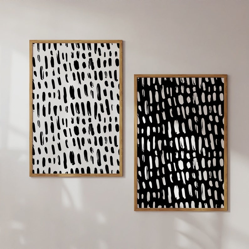Puede incluir: Dos impresiones art&iacute;sticas abstractas enmarcadas. Una impresi&oacute;n presenta un fondo blanco con trazos de pincel negros, y la otra tiene un fondo negro con trazos blancos. Ambas est&aacute;n en marcos de madera.