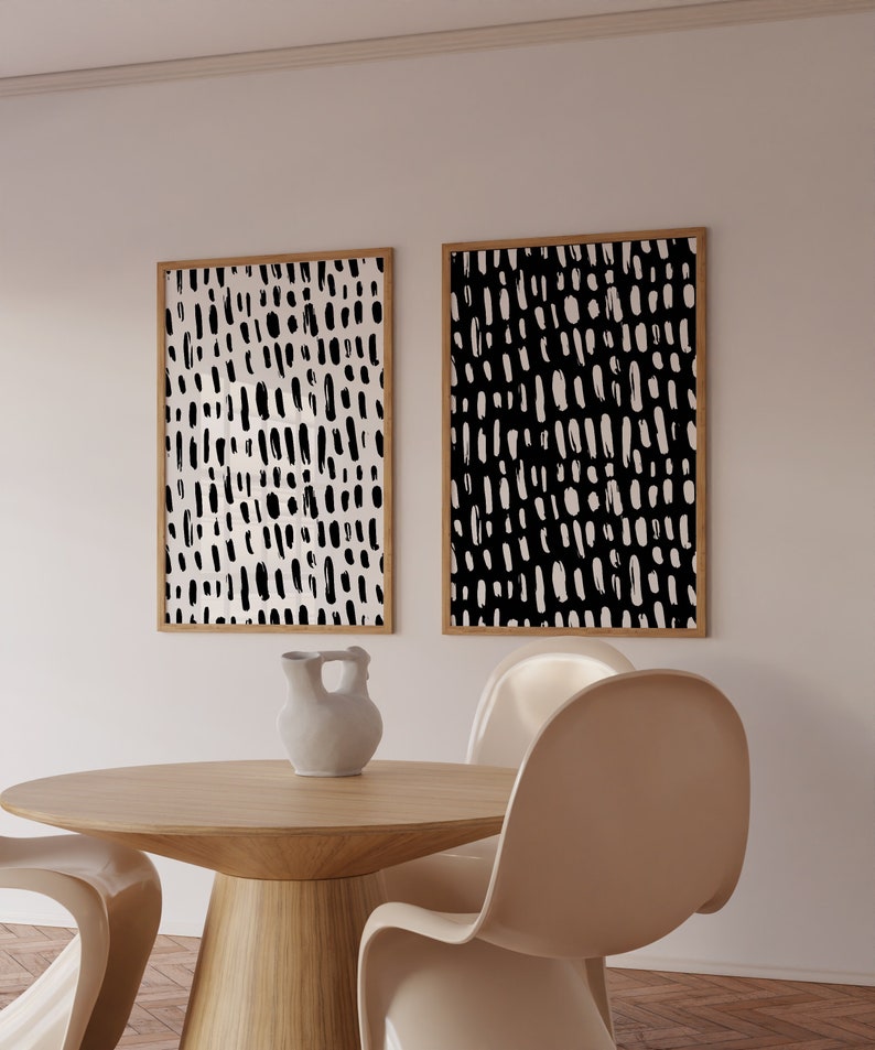 Puede incluir: Dos impresiones art&iacute;sticas abstractas enmarcadas con un patr&oacute;n de trazos en blanco y negro. Las impresiones se exhiben en una pared blanca sobre una mesa de madera con un jarr&oacute;n y sillas. El arte tiene un dise&ntilde;o minimalista.