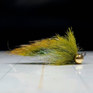 May include: A green and white fly fishing lure with a gold bead head.