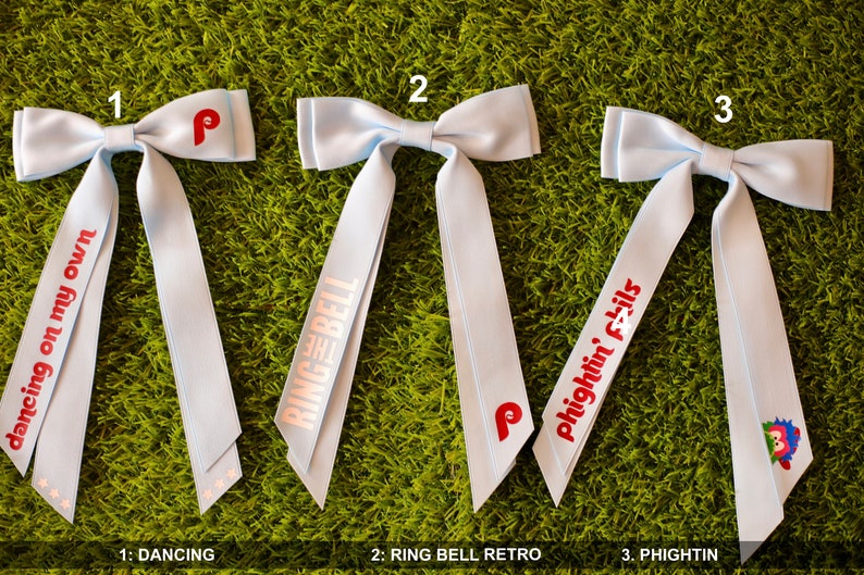 May include: Three light blue hair bows with red and white text. The first bow has the text "dancing on my own". The second bow has the text "THE RING BELL". The third bow has the text "Phightin' Phils".