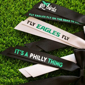 May include: Black and white ribbon bows with green text. The text on the ribbons reads "go birds", "FLY EAGLES FLY ON THE ROAD TO VICTORY", "FLY EAGLES FLY", and "IT'S A PHILLY THING".