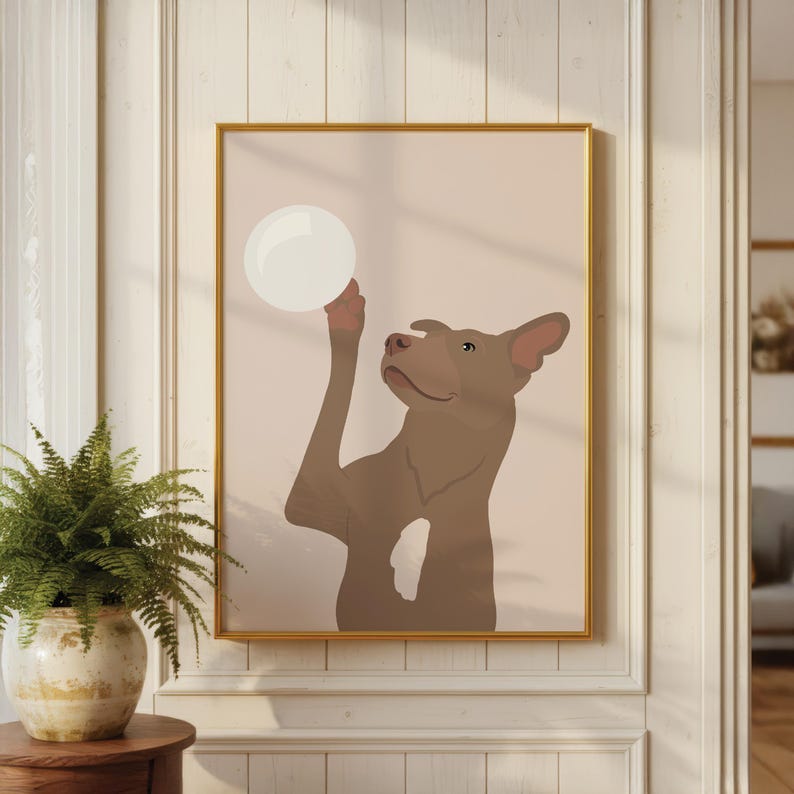 May include: A framed art print showing a brown dog with a white bubble. The dog is illustrated in a minimalist style against a light pink backdrop. The frame is gold, and the artwork is displayed on a white wall.