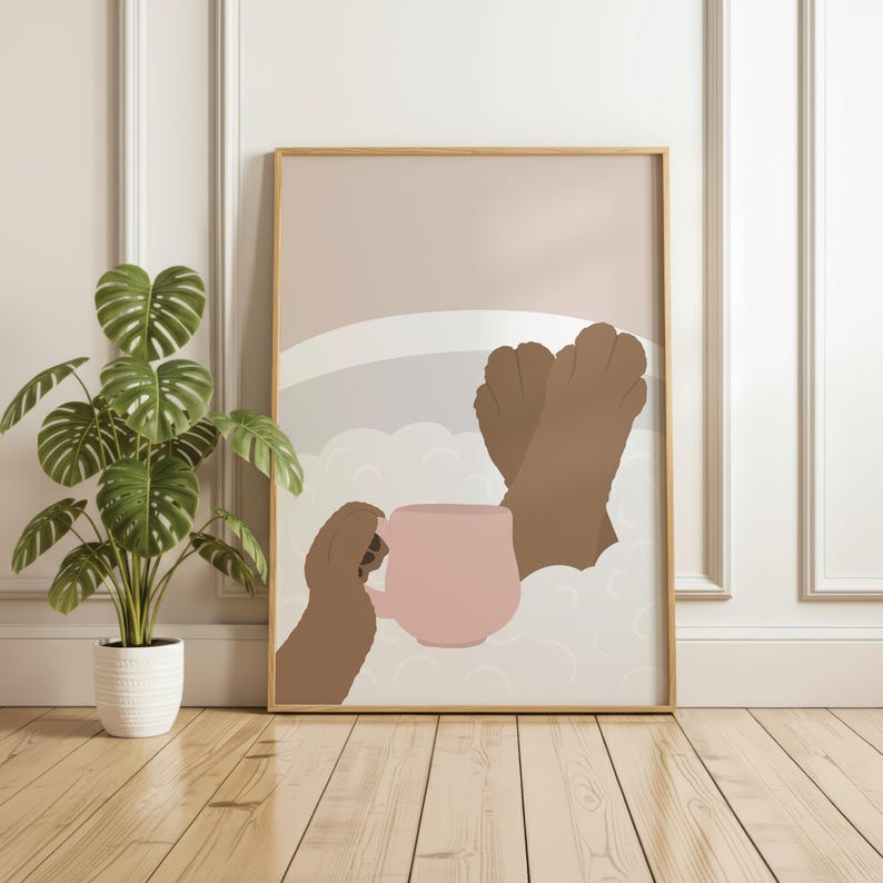 May include: A framed art print shows a person relaxing in a bath, holding a pink mug. The artwork has a minimalist style with brown skin tones, a light pink mug, and a neutral colour palette. A potted plant sits beside the framed art.