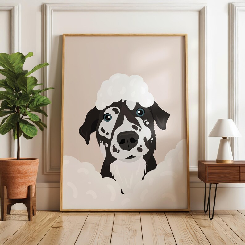 May include: A framed art print showing a cartoon dog with black and white markings and blue eyes. The dog has a white, fluffy cloud-like shape on its head and is surrounded by similar cloud shapes. The artwork has a light pink background.