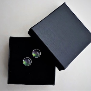 Peut inclure: Une paire de boucles d'oreilles rondes en argent avec des pierres vertes et noires irisées dans une boîte noire.