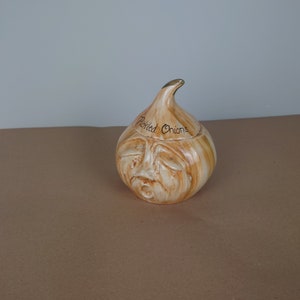 May include: A ceramic onion-shaped jar with a distressed brown and white glaze. The jar has a face with a frowning expression and the words "Pickled Onions" written on the top.