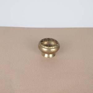 May include: A small, round brass incense burner with a wire mesh top. The burner has intricate designs etched into the surface.