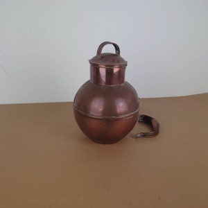 May include: A copper pitcher with a lid and a handle. The pitcher is round and has a shiny finish.