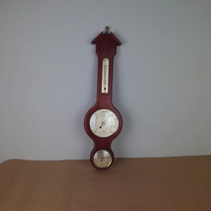 Vintage wooden nautical barometer with temperature gauge. Historic traditional FCC precision weather station barometer.
