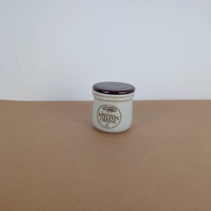 May include: A white ceramic jar with a brown lid. The jar has a label that reads "English Blue Stilton Cheese".