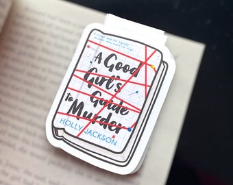 May include: A white sticker with a red and black illustration of a book titled "A Good Girl's Guide to Murder" by Holly Jackson. The book cover is covered in red string and has several push pins.