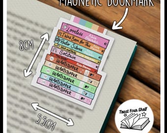 Op de afbeelding: Een magnetische bladwijzer met een stapel kleurrijke boeken met titels zoals "Loveless", "I Was Born for This", "Radio Silence", "Solitaire" en "Heartstopper". De bladwijzer is 8 cm hoog en 5,5 cm breed. De bladwijzer bevat ook de tekst "Treat Your Shelf" met een ster aan elke kant.