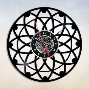 May include: Black vinyl record clock with a geometric design and a clock face with Roman numerals. The clock hands are red and black.
