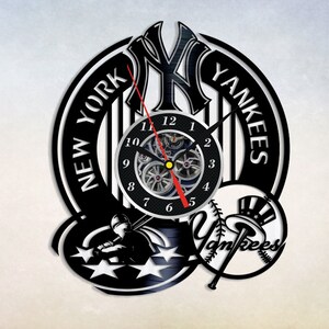 May include: Black and white vinyl record clock featuring the New York Yankees logo. The clock has a black background with white stripes and the words "New York Yankees". The clock face is a white circle with black numbers and hands. The clock is surrounded by a black and white image of a baseball player and a baseball with the Yankees logo.