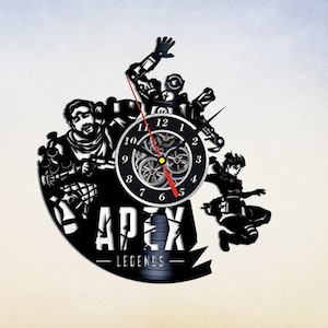 May include: A black vinyl record clock featuring characters from the video game Apex Legends. The clock face is a circular clock with black numbers and a red second hand. The characters are silhouetted in black and the text "Apex Legends" is printed in white below the clock face.