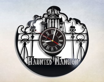 May include: Black vinyl record clock featuring a silhouette of the Haunted Mansion from Disneyland. The clock face is a traditional Roman numeral design with black hands and a white background. The words "Haunted Mansion" are printed in white below the clock face.