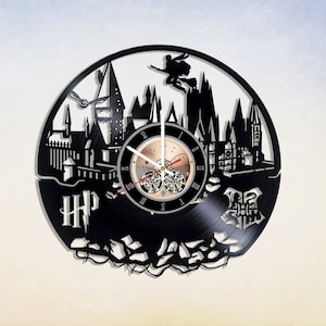 Peut inclure: Horloge en vinyle noir représentant une silhouette du château de Poudlard, une figure volante avec une baguette magique et les lettres "HP".