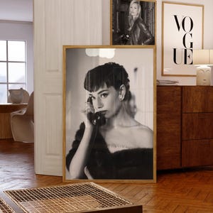 Peut inclure: Photographie en noir et blanc d'une femme au t&eacute;l&eacute;phone. La photo est encadr&eacute;e dans un cadre en bois et est accroch&eacute;e &agrave; un mur. Le mur est blanc et il y a d'autres photos encadr&eacute;es sur le mur.