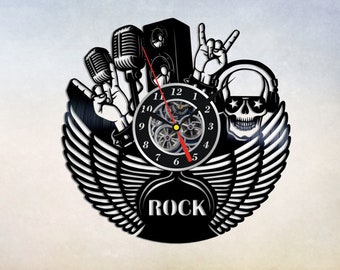 Könnte beinhalten: Schwarze Schallplattenuhr mit einem Schädel, der Kopfhörer, Mikrofone und einen Lautsprecher trägt. Das Zifferblatt der Uhr hat römische Ziffern und das Wort "ROCK" ist unter dem Zifferblatt der Uhr gedruckt.