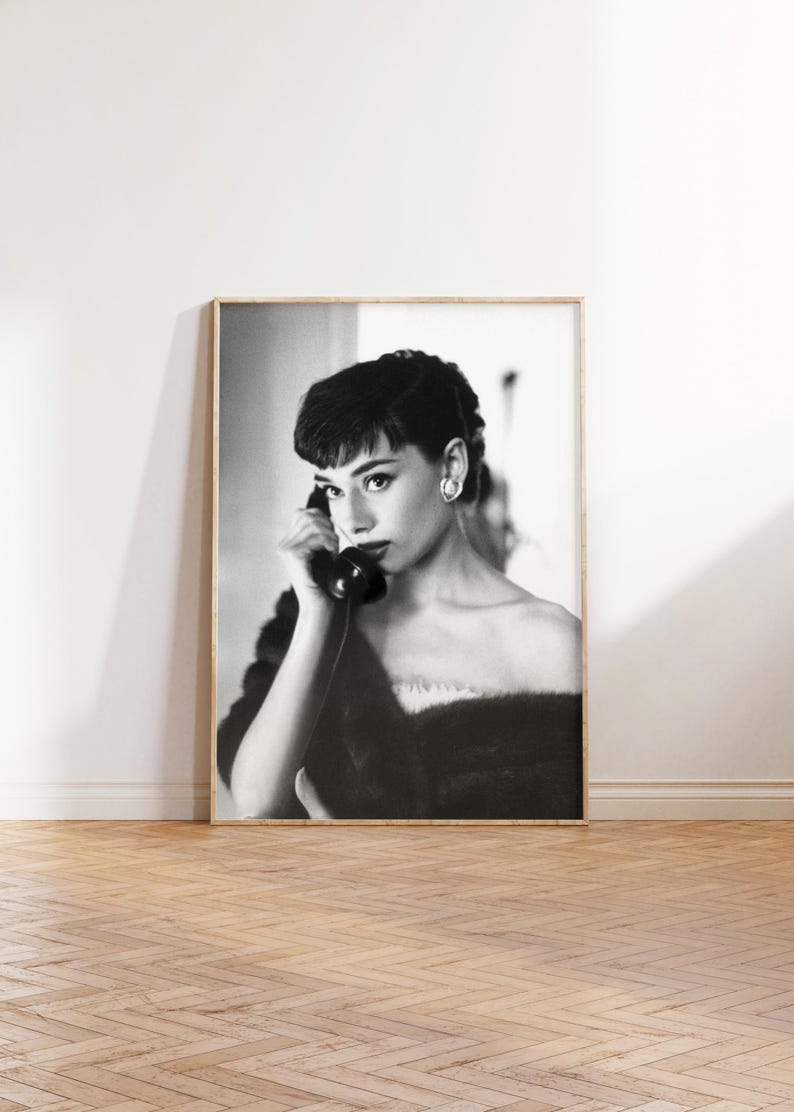 Peut inclure: Photographie en noir et blanc d'une femme aux cheveux courts et fonc&eacute;s, portant un col en fourrure et tenant un t&eacute;l&eacute;phone rotatif vintage &agrave; son oreille.