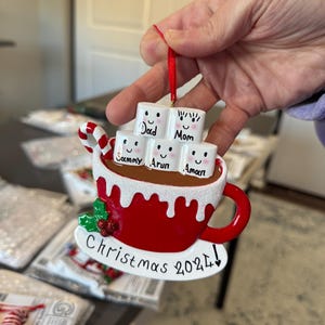 Christmas 2025, a charming keepsake featuring your loved ones’ names on smiling marshmallows. This Custom Marshmallow Family Ornament – Holiday 2025 Keepsake is perfect for cozy Christmas vibes and makes a great addition to your tree. Designed as a Christmas Mug Ornament with Names – Family of 5 – 2025,  Our Hot Chocolate Family Ornament – Christmas Tree Decor 2025 Ornament this listing.