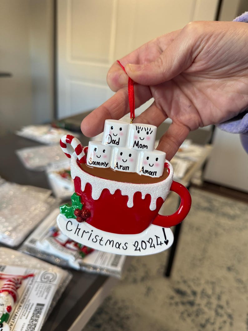Christmas 2025, a charming keepsake featuring your loved ones’ names on smiling marshmallows. This Custom Marshmallow Family Ornament – Holiday 2025 Keepsake is perfect for cozy Christmas vibes and makes a great addition to your tree. Designed as a Christmas Mug Ornament with Names – Family of 5 – 2025,  Our Hot Chocolate Family Ornament – Christmas Tree Decor 2025 Ornament this listing.