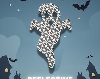 May include: A ghost-shaped cutout featuring a silver and black geometric triangular pattern. The ghost is centered against a blue background with silhouettes of bats and houses. The word REFLECTIVE is printed in white capital letters at the bottom.