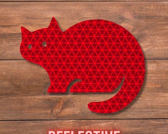 May include: A red cat-shaped decal featuring a repeating geometric triangle pattern across its surface. The silhouette depicts a cat in a seated position with its tail curved around its body. The word REFLECTIVE is printed in white below.